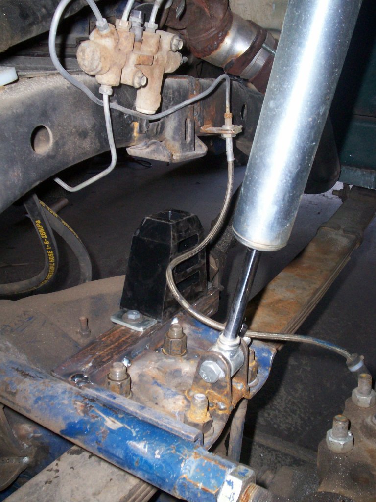 Close-up of vehicle rear axle suspension with leaf spring, shock, and brake lines.