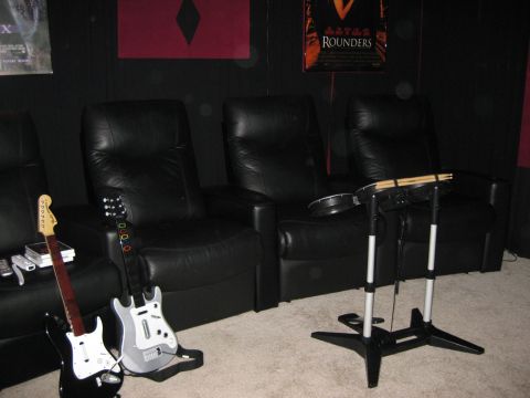 1979 Ford Bronco - Gaming guitars and a drum set are set up in front of a row of black leather recliners in a home theater setting.