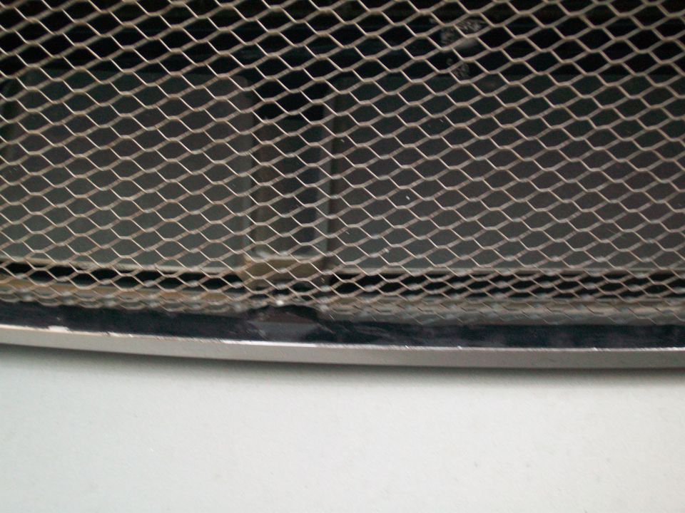 Close-up of a diamond-patterned metal grille with a chrome trim piece below