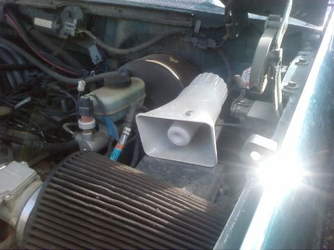 1995 Ford Bronco - The engine compartment shows various components, including an aftermarket siren, amidst wiring and hoses.