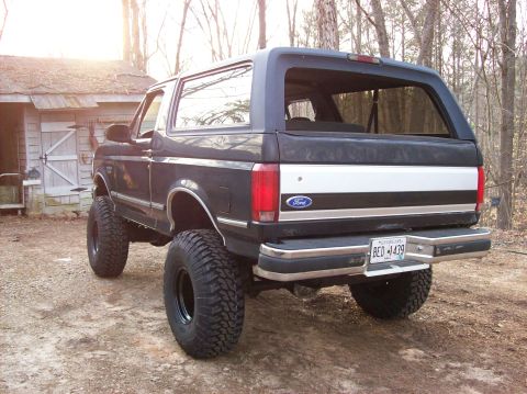 1992 Ford Bronco - Rear view of a lifted 1992 Ford Bronco with custom wheels and tires, parked outdoors.
