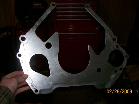 1995 Mercury Grand Marquis - A metal transmission bell housing adapter plate is shown, with a red toolbox visible behind it.
