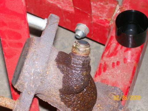 1995 Mercury Grand Marquis - A close-up of a corroded brake caliper part, likely from an older vehicle, is shown on a red stand.