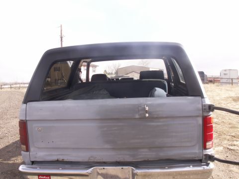 1986 Ford Bronco - Rear view of a 1986 Ford Bronco with a primer finish and black hardtop.