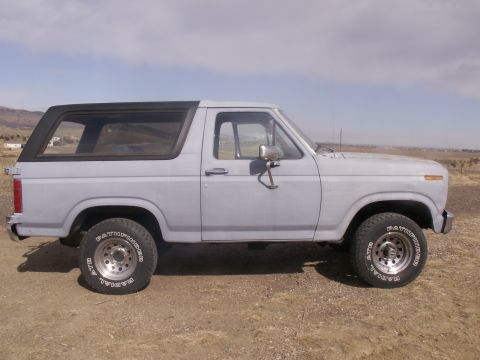 1986 Ford Bronco - This 1980s Ford Bronco is shown from the side, with a light blue exterior and a black removable top.