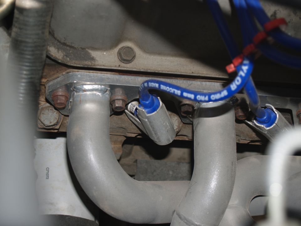 Close-up of shorty exhaust headers and blue Taylor spark plug wires on an engine