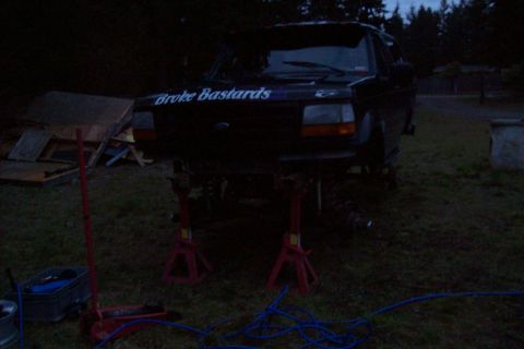 1995 Ford Bronco - A black Ford Bronco is elevated on jack stands in a grassy area, with text visible on its hood.