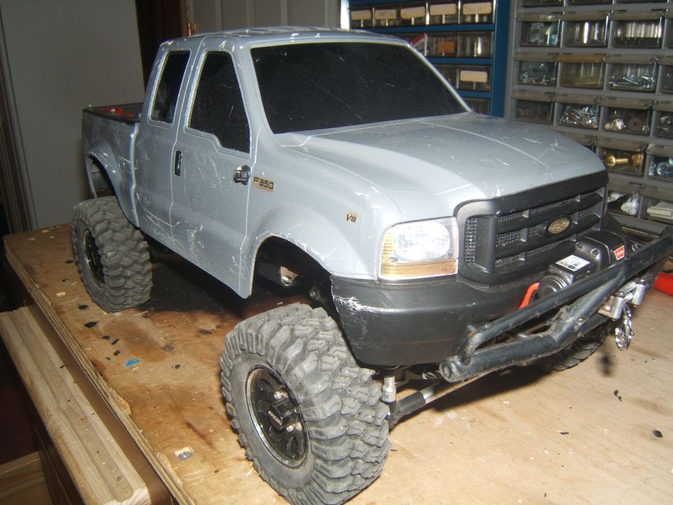 Silver RC truck model with large tires and a winch on the front bumper. F-350 badge visible on fender