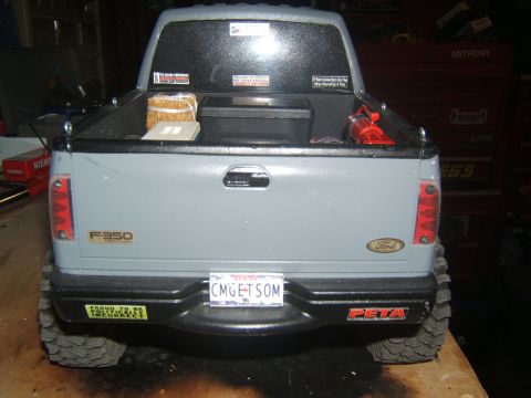 1988 Ford Bronco - The rear view of a gray Ford F-350 Super Duty pickup truck with a black bumper and a license plate that reads "CMGETSOM". A yellow sticker…