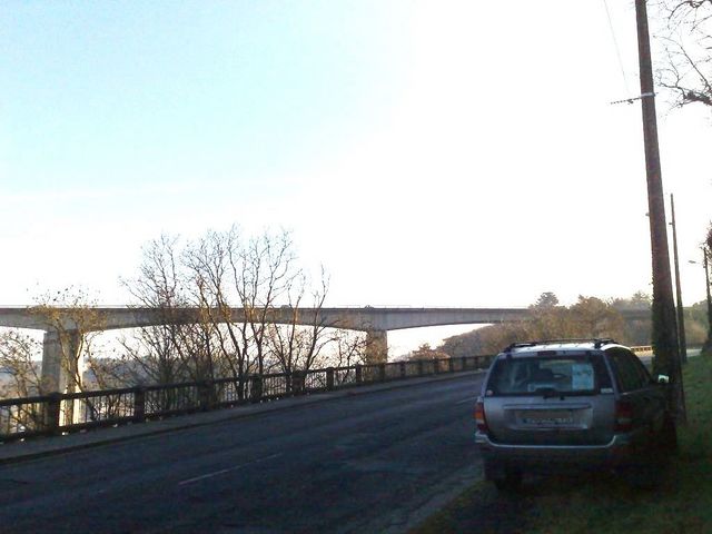 Photo of an SUV on a roadway leading toward a long highway bridge