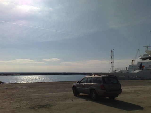 Photo of a Jeep Grand Cherokee parked at a harbor near a docked ship