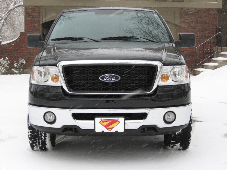 Black Ford F-150 pickup truck front view in snow with Superman license plate