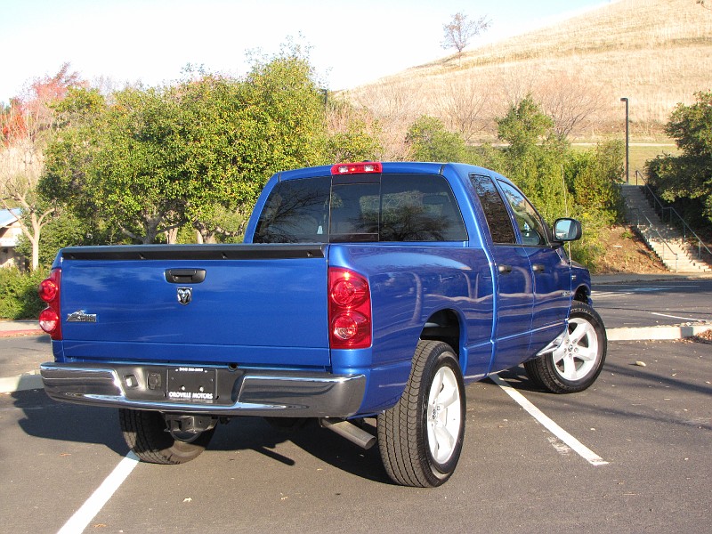 Photo of a blue Dodge Ram pickup, rear three-quarter view in a parking lot