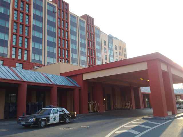 Photo of a large red-and-tan hotel with a CHP police car under the canopy