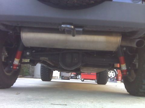 2008 Jeep Wrangler - The underside of a Jeep Wrangler is shown, featuring the exhaust system, rear differential, and suspension components. The vehicle is parke…