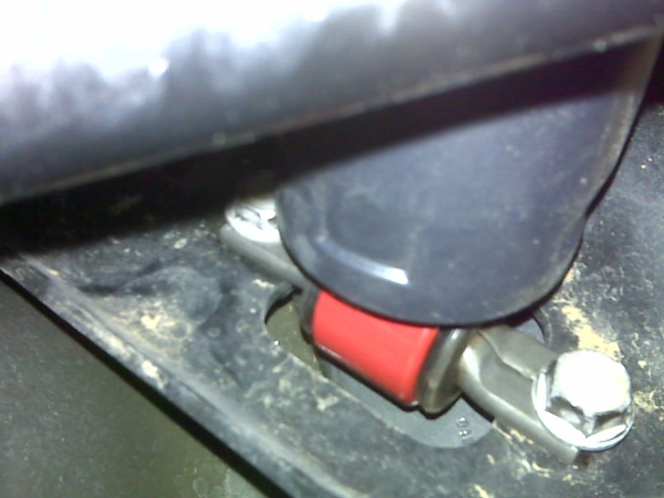 Close-up of a red shock absorber with a silver bracket and hex bolt on a black vehicle frame.