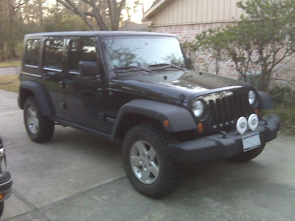 Black 2008 Jeep Wrangler, four-door, with aftermarket fog lights parked on a driveway.