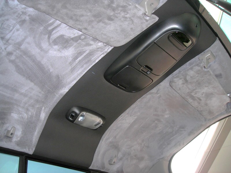 Photo of a vehicle headliner with overhead console and gray suede trim
