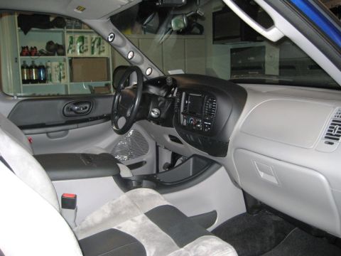 2007 Ford Mustang - Photograph of a customized truck front interior with dashboard, steering wheel and suede seats, not a document.