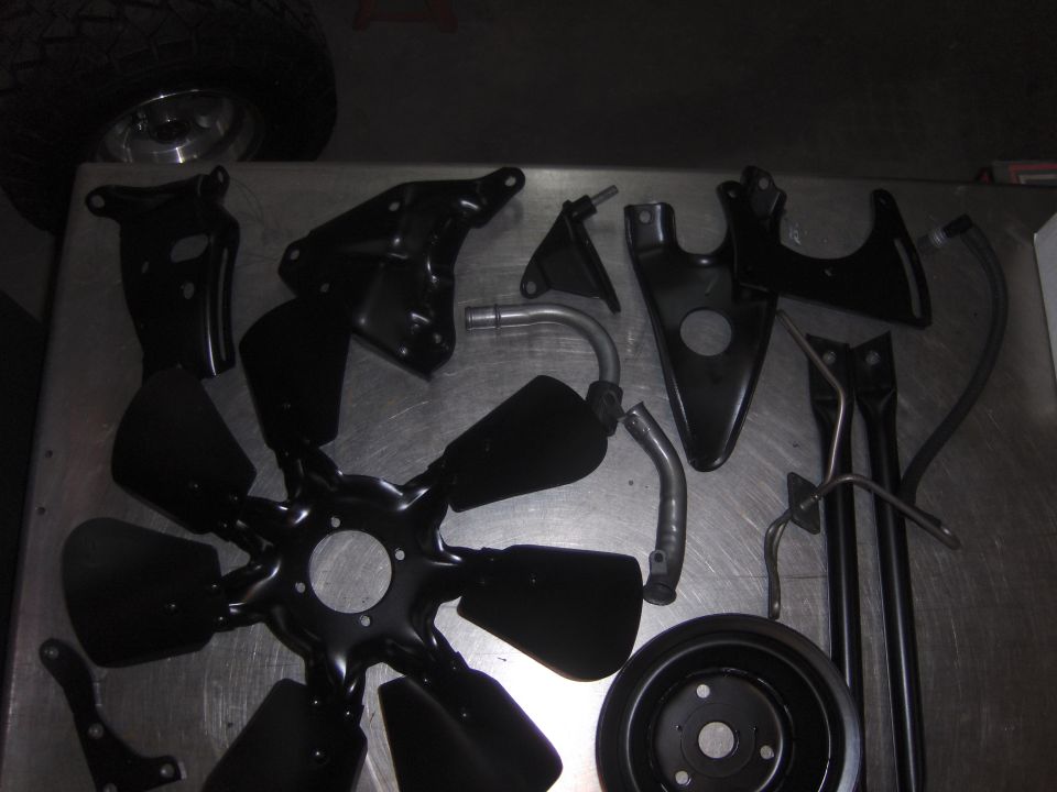 Black painted engine fan parts and a tire on a metal surface