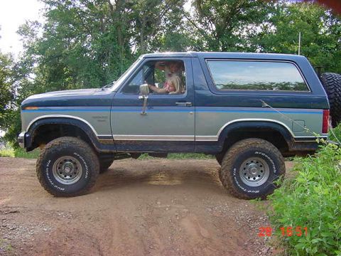 1986 Ford Bronco - Side view of a 1986 Ford Bronco on a dirt path.
