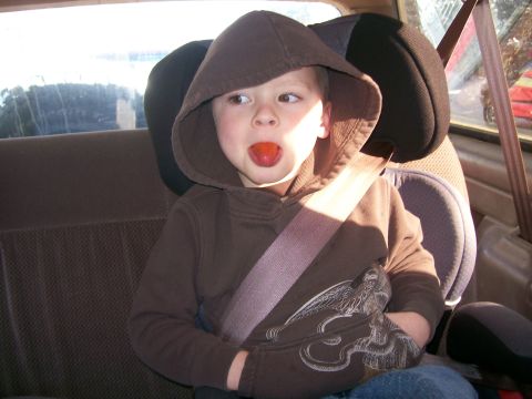 1993 Ford Bronco - A young child wearing a brown hooded sweatshirt sits in the back seat of a vehicle, with a piece of food in their mouth. The child is secur…