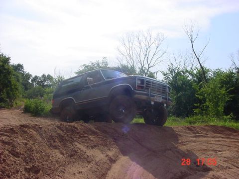 1986 Ford Bronco - A Ford Bronco navigates an off-road trail on a sunny day.