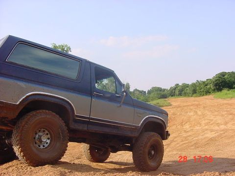 1986 Ford Bronco - This 1986 Ford Bronco is captured in a three-quarter front view while navigating a dirt terrain.