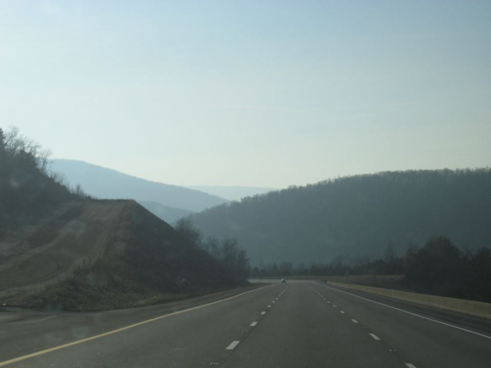 Open highway descending toward a gap in forested hills
