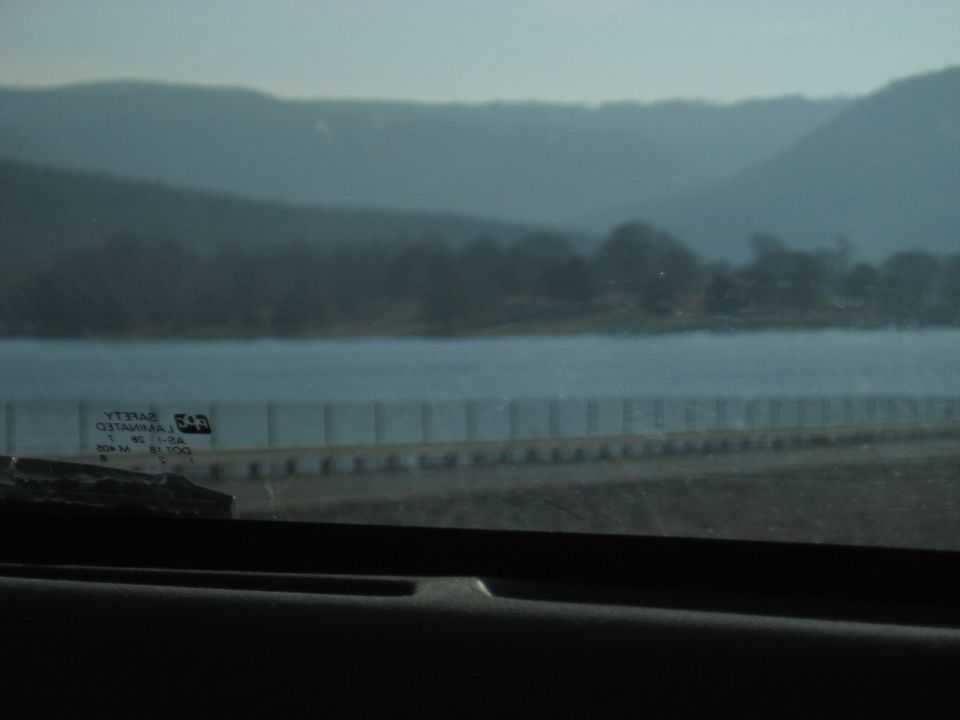 Lake and bridge causeway seen through a vehicle window with a sticker