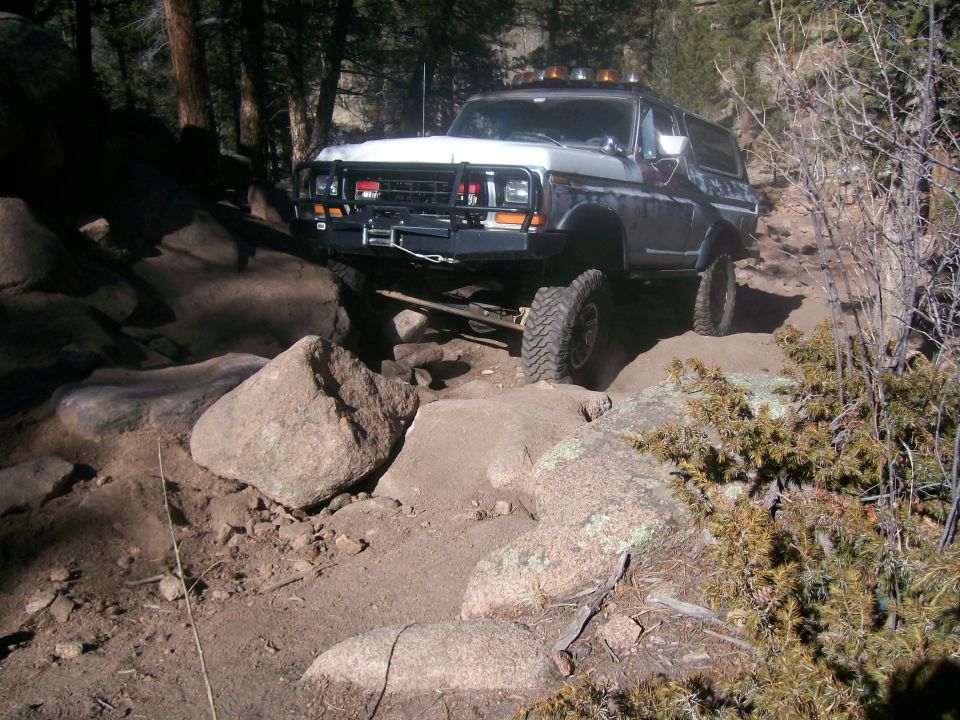 Lifted Ford Bronco off-roading on a rocky trail.