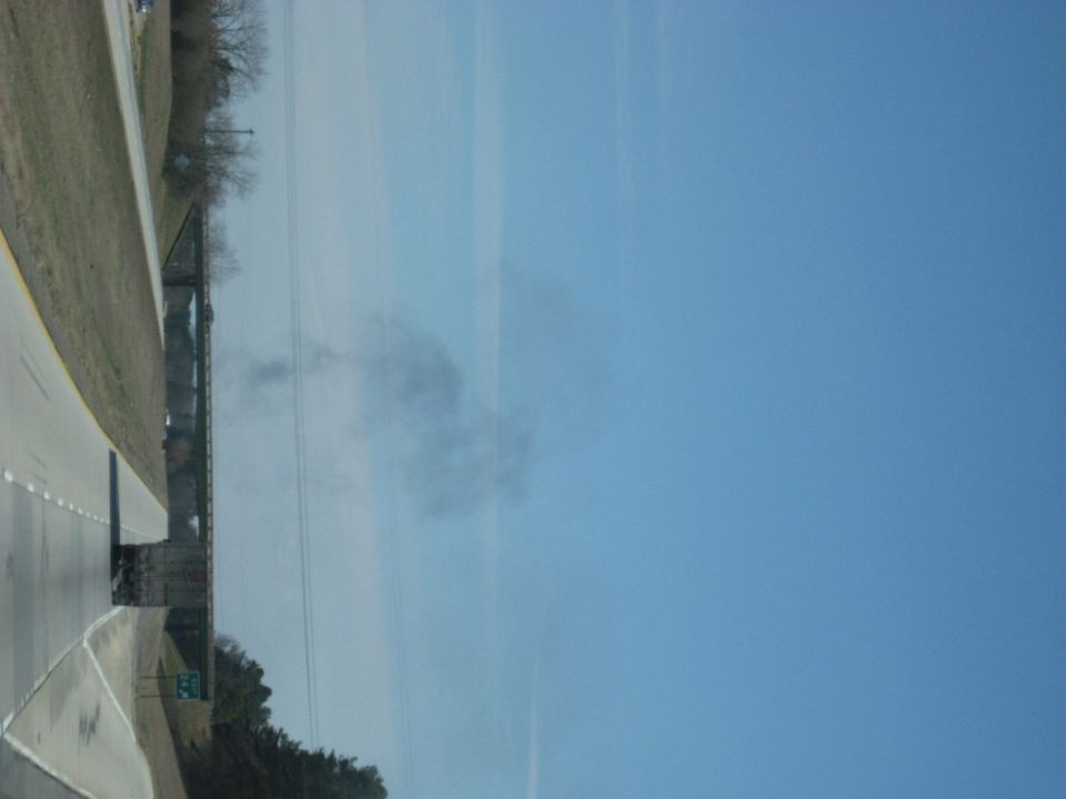 Rotated photo of a roadside with a smoke plume and power lines