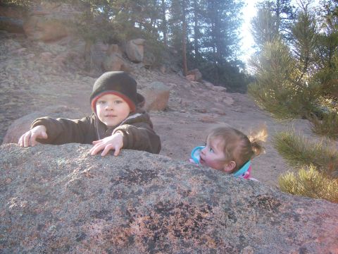1993 Ford Bronco - Two young children are peeking over a large rock in a wooded, rocky outdoor setting.