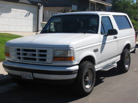 1988 Ford Bronco - This white Ford Bronco is shown from the front 3/4 angle, revealing its grille and headlights.