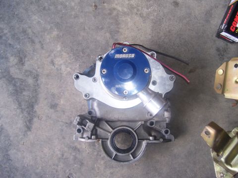 1990 Ford Mustang - A blue and silver Moroso electric water pump is shown mounted on a gray concrete surface. The pump has red and black wires attached to it a…
