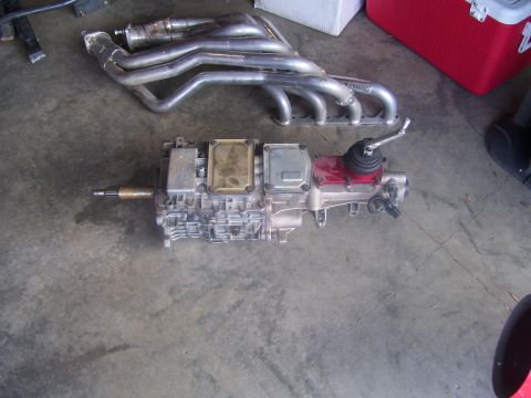 1990 Ford Mustang - A manual transmission and a set of exhaust headers are laid out on a concrete floor.