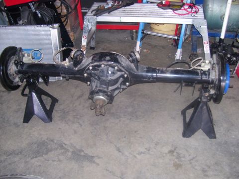1990 Ford Mustang - A rear axle assembly, likely from a Ford Mustang, is supported by two black jack stands on a concrete floor. The assembly features brake dr…