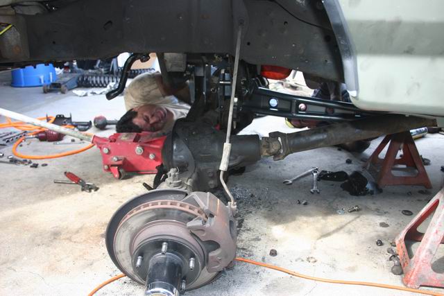 Underside of a vehicle being worked on, showing suspension and drivetrain components.