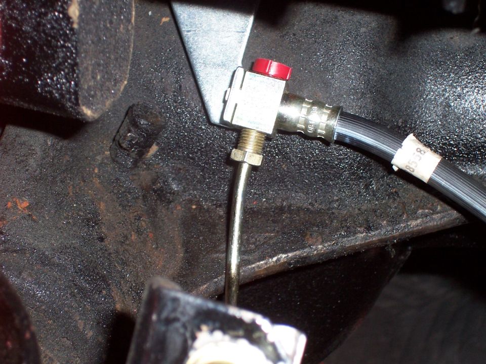 Close-up of a vehicle brake line with a red cap and a label reading "8558".