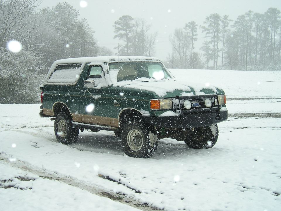 1989 Ford Bronco in a snowy field during a snowfall.