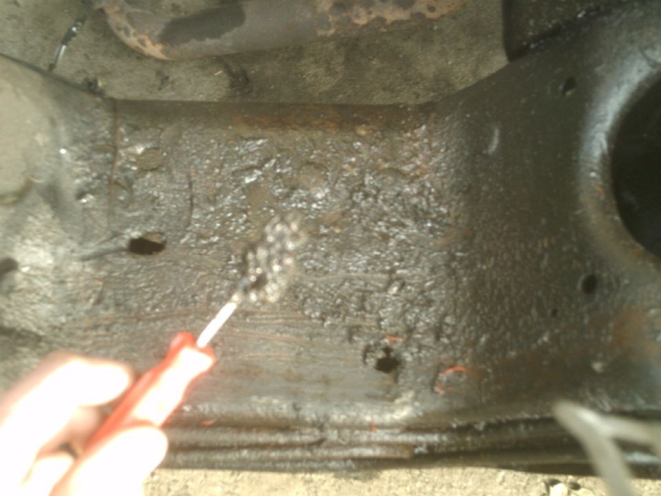 Wire brush cleaning a greasy, dirty vehicle part.