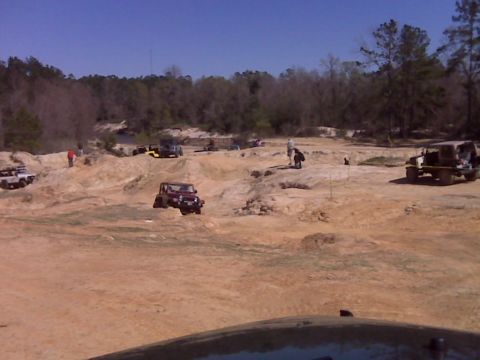 2008 Jeep Wrangler - Several off-road vehicles are navigating a sandy, rocky terrain with trees in the background. One red Jeep Wrangler is prominently featured…