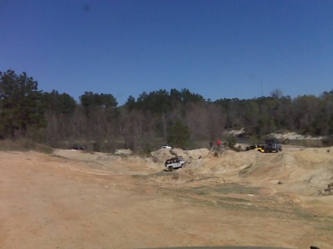 2008 Jeep Wrangler - A group of off-road vehicles are navigating a sandy, hilly terrain with trees in the background. One white Jeep Wrangler is visible on the…