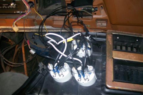 1982 Ford E350 - The interior of a vehicle shows a cluster of gauges with wiring harnesses connected to them, situated below the dashboard and near a vent.