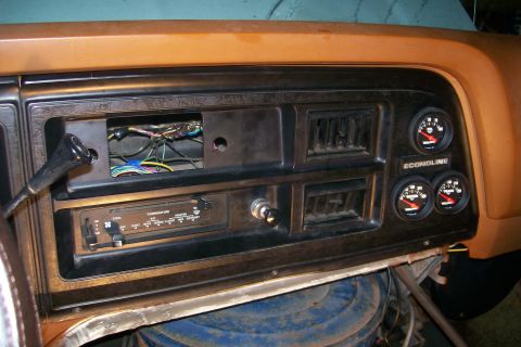 1982 Ford E350 - The interior dashboard of a Ford Econoline van shows a radio slot with wires, climate controls, and three aftermarket gauges mounted to the…
