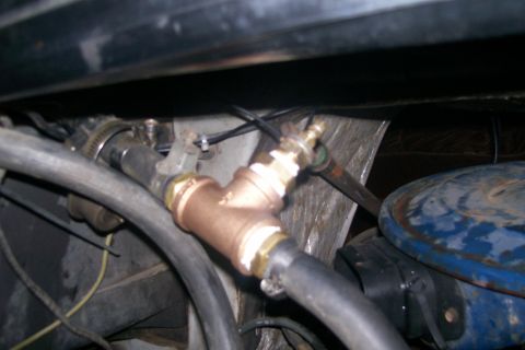 1982 Ford E350 - A close-up view shows a brass T-fitting connected to black hoses, likely part of a vehicle's cooling or fluid system. The fitting is secure…