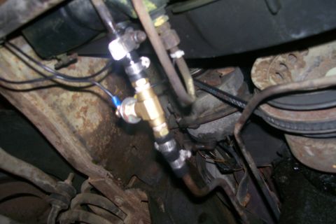 1982 Ford E350 - A close-up view of a brass T-fitting with a pressure sensor attached to a fuel line, secured with hose clamps. The fitting is part of a mod…