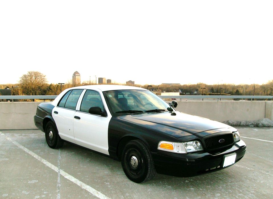 Black and white sedan parked on a concrete surface, city skyline in background