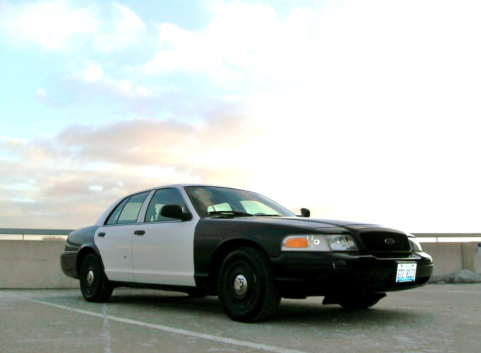 Two-tone black and white 2004 Ford Crown Victoria parked on a concrete surface under a cloudy sky