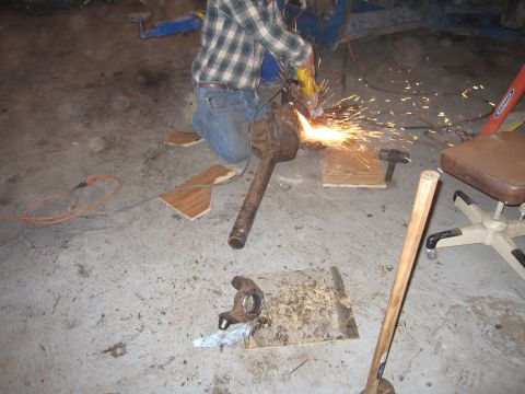 1992 Ford Bronco - A person is using an angle grinder on a metal object in a workshop setting, with various tools and parts scattered around.
